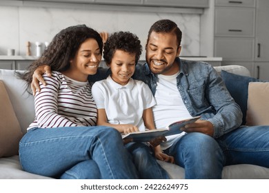 Cheerful African American Family With Little Son Reading Book Together At Home, Caring Black Parents Bonding With Their Preteen Male Child, Relaxing On Couch In Living Room, Copy Space - Powered by Shutterstock