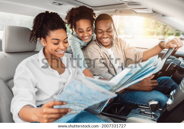 Cheerful African\
American Family Looking At Road Map Sitting In Car. Parents And\
Daughter Choosing Destination For Summer Road Trip Together. Local\
Tourism Concept. Selective\
Focus