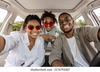 Cheerful African American Family Of Three Posing In Car, Wearing Sunglasses. Parents And Preteen Daughter Traveling By Automobile In Summer. Road Trip Adventure Concept