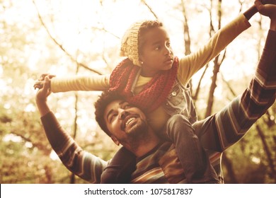 Cheerful African American Father Carrying Daughter On Shoulders.