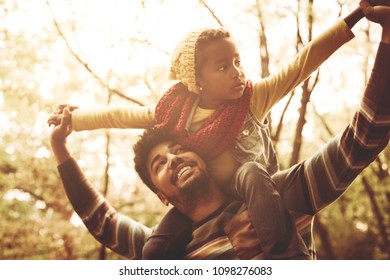 Cheerful African American Father Carrying Daughter On Shoulders.