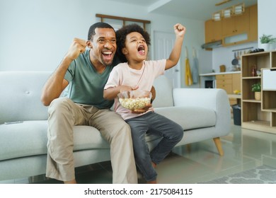 Cheerful African American Father and his little boy watching and cheering sports games competition together at home, celebrate - Powered by Shutterstock