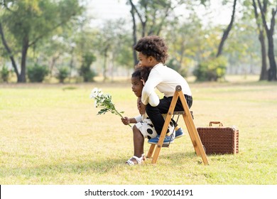 Cheerful African American Little Boy And Girl Playing And Hugging Together On Stepladder In The Park. Children With Curly Hair Having Fun Together Outdoor. Black Kid People Enjoying Outside