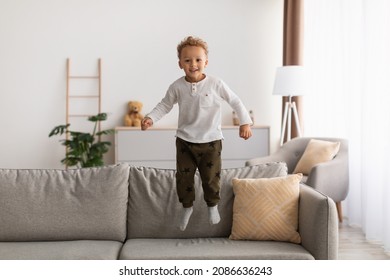 Cheerful African American Little Boy Jumping Having Fun Posing In Mid-Air Smiling To Camera At Home. Carefree Kid Playing Spending Time Indoor. Childhood Leisure, Happiness Concept - Shutterstock ID 2086636243