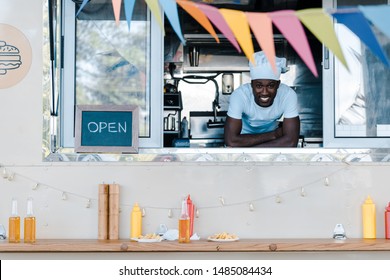 Cheerful African American Man In Chef Uniform Smiling From Food Truck 