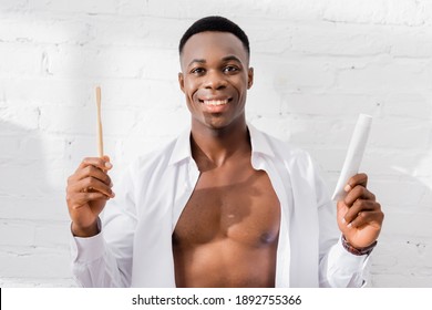 Cheerful African American Man Holding Toothpaste And Toothbrush At Home