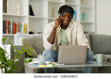 Cheerful African American Man Making Phone Call While Typing On Laptop At Home.