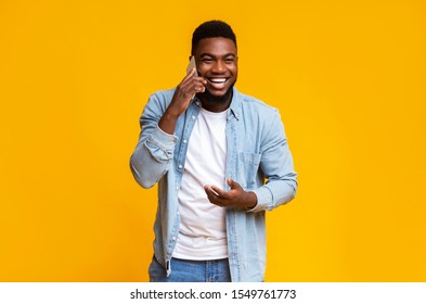 Cheerful African American Man Talking On Phone And Laughing Out Loud Over Yellow Studio Background, Free Space