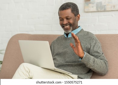 Cheerful African American Man Waving Hand During Video Call On Laptop