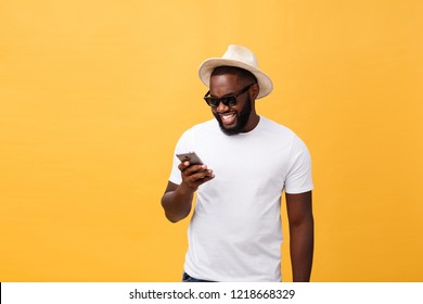 Cheerful African American man in white shirt using mobile phone application. happy dark skinned hipster guy read news from social network in mobile phone.