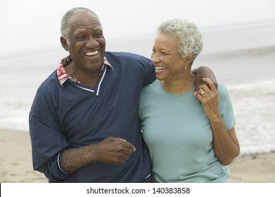 Cheerful African American mature couple with arms around at the beach