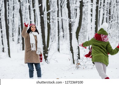 Cheerful African American Mom Playing Snowballs With Daughter In Winter Park