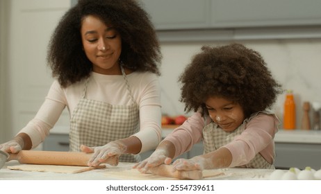 Cheerful African American mother woman teach little daughter child kid girl make flattening dough with rolling-pins in kitchen happy family use ecological products ingredients cooking together smiling - Powered by Shutterstock