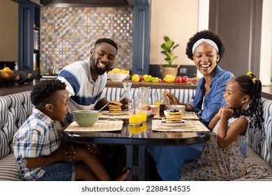 Cheerful african american parents and children talking while having breakfast at dining table. Unaltered, family, togetherness, childhood, lifestyle, food, healthy, happy and home concept. - Powered by Shutterstock