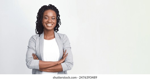 Cheerful African American professional woman in a grey blazer, isolated on a white background, wide frame with copy space for text. - Powered by Shutterstock