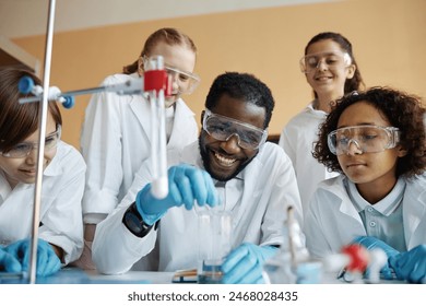 Cheerful African American teacher and group of ethnically diverse kids doing lab experiment during Chemistry class - Powered by Shutterstock