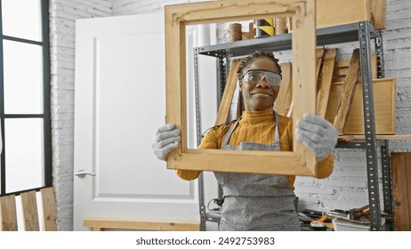 A cheerful african american woman with braids working indoors at a workshop, holding a wooden frame. - Powered by Shutterstock