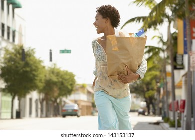 Cheerful African American Woman Carrying Grocery Bag While Walking On Street