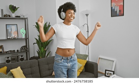 Cheerful african american woman enjoys music with headphones in a cozy living room setting. - Powered by Shutterstock