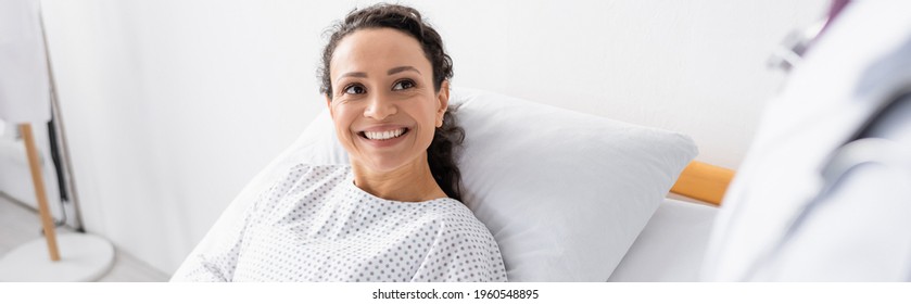 cheerful african american woman smiling near doctor on blurred foreground, banner - Powered by Shutterstock