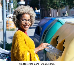 Cheerful African American Woman Throwing Plastic Bottle Into Recycling Bin On The Street