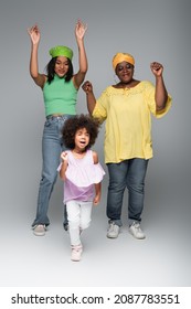 Cheerful African American Women With Girl In Trendy Clothes Dancing On Grey