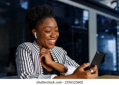 Cheerful african american young businesswoman laughing while talking on video call over mobile phone in office - Powered by Shutterstock