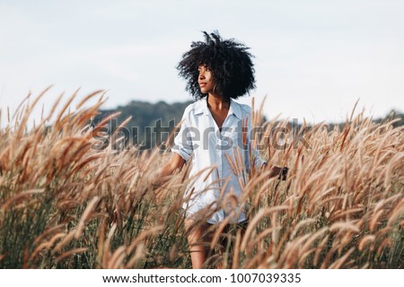 cheerful african american young woman on the field at sunset