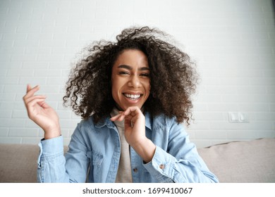 Cheerful african teenage girl blogger talking to camera recording vlog. Happy mixed race young woman laughing making video call at home. Funny social media influencer streaming blog. Webcam view.