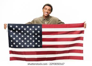 Cheerful African-American guy holding in hands american flag, looking at the camera and smiling isolated on white background, Flag Day concept - Powered by Shutterstock
