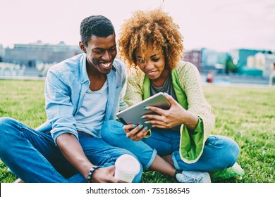 Cheerful Afro American Best Friends Watching Movie Online Satisfied With High Speed Internet Connection Outdoors,happy Couple In Love Laughing On Funny Videos On Tablet Sitting On Lawn Together