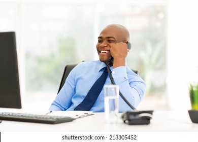 cheerful afro american businessman talking on landline phone in office - Shutterstock ID 213305452