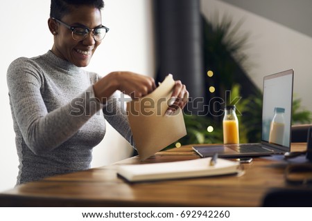 Cheerful afro american businesswoman in trendy eyewear feeling happy getting letter with documents for successful project,happy female freelancer satisfied with occupation receiving job offer paper