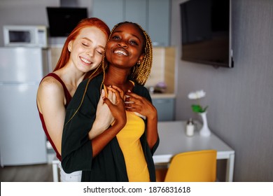 cheerful afro and european lesbian women at home on the bed