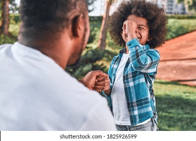 Cheerful Afro-American Child Holding His Hand To His Forehead And Smiling While Playing With His Dad