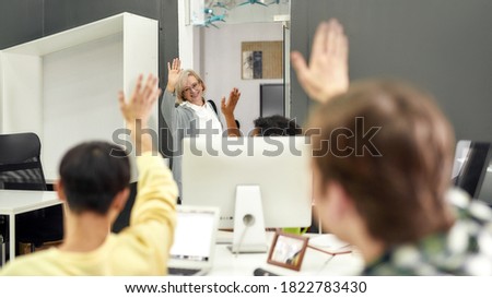 Cheerful aged woman, senior intern waving, saying goodbye to her young colleagues while leaving office after first day at work, Selective focus, Web Banner