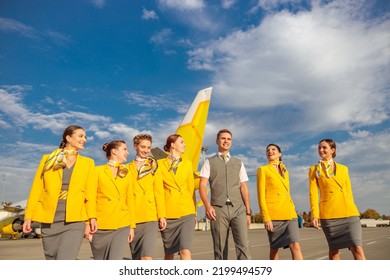 Cheerful Aircrew Walking Down Airfield Under Cloudy Sky