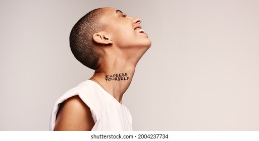 Cheerful androgynous woman with express yourself written on neck. Androgynous woman having short hairstyle smiling with her eyes closed.