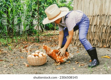 Cheerful Asian boy farmer runs catch mischievous chickens, farm animals and collects eggs in basket in hen farm to collect chicken eggs to donate for food and sell commercially. - Powered by Shutterstock