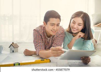 Cheerful Asian Couple Looking At Construction House Plan