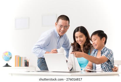 Cheerful Asian Family Watching Something On Laptop