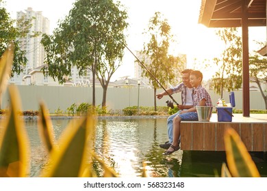 Cheerful Asian Father And Son Fishing In Pond