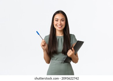 Cheerful asian female volunteer conducting survey, writing down people answers in clipboard, holding pen and papers smiling friendly, standing white background enthusiastic - Shutterstock ID 2093622742