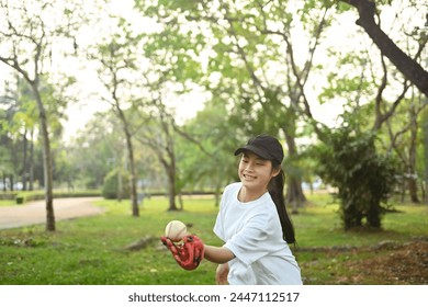 Cheerful Asian girl in leather glove playing baseball in sunny day at public park - Powered by Shutterstock