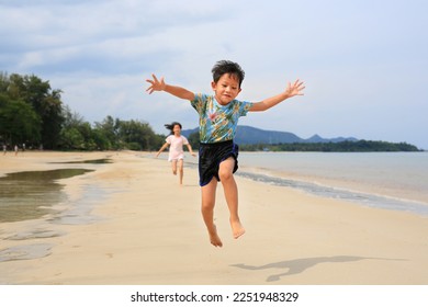 Cheerful Asian little boy child and girl kid having fun jumping and running on tropical sand beach at sunrise. Happy family sister and brother enjoy in summer holiday. - Shutterstock ID 2251948329
