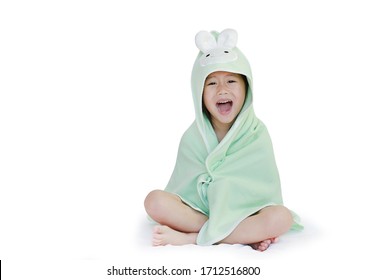Cheerful asian little child girl smiling cover body under towel after bath sitting on bed against white background with copy space.
