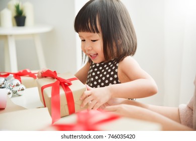 Cheerful Asian little kid celebrating with a brown gift box for Birthday, Christmas and New year in a white room. Happy Asian family at the house. Copy space.