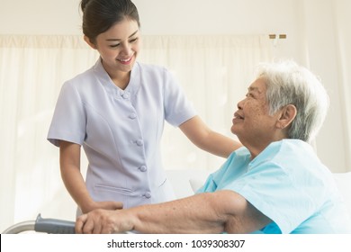 Cheerful Asian Nurse Visiting Elderly Patient To Check Up After Surgery In Hospital For Giving Physical Therapy And Encouragement.