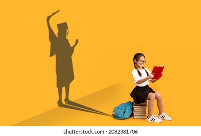 Cheerful Asian Schoolgirl Reading, Sitting On Book Stack, Shape Of Female In Graduation Costume Over Yellow Background, Kid Dreaming About Master Degree, Conceptual Image, Panorama - Shutterstock ID 2082381706