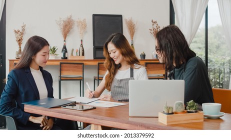 Cheerful Asian small business owners couple meeting with consultant talking about business plan and finance in cafe. Young Japanese agent consider signing contract insurance together at restaurant. - Powered by Shutterstock